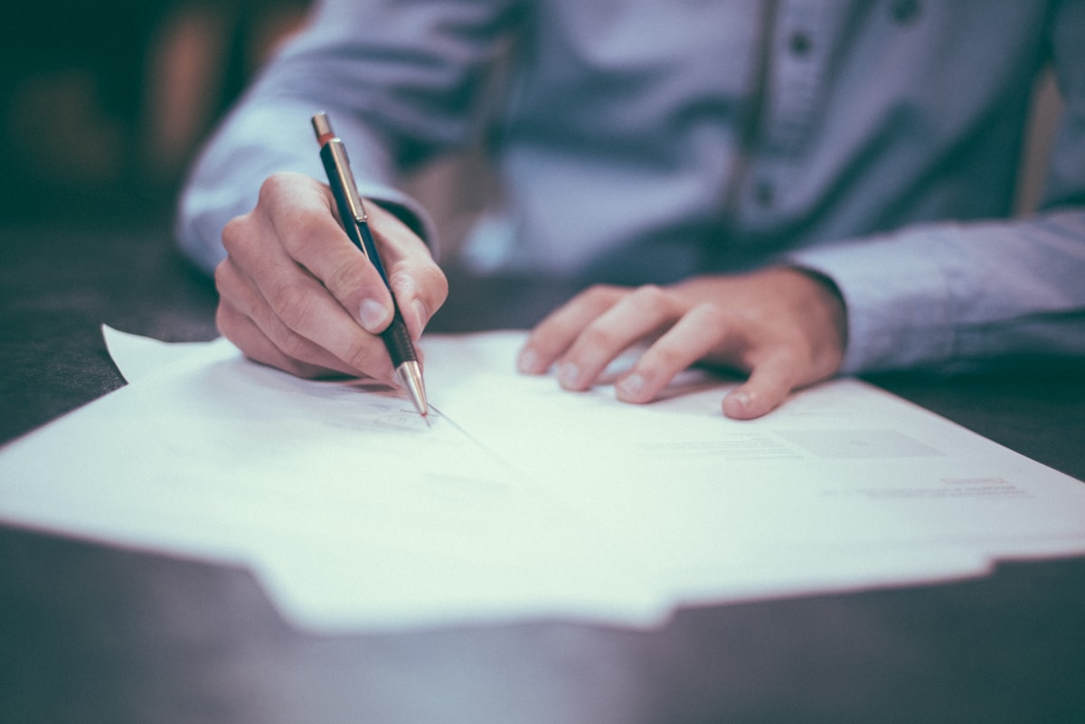 A person writing on paper with a pen